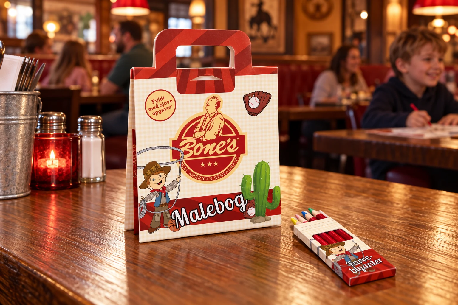 Den foldede Bone’s malebog og farveblyanter på restaurantbordet